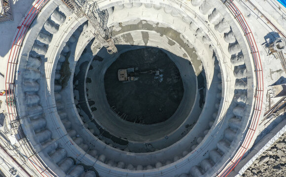 Aerial view of a deep circular construction shaft with an excavator at the bottom and concrete reinforced walls Sariyer, Istanbul, Turkiye.