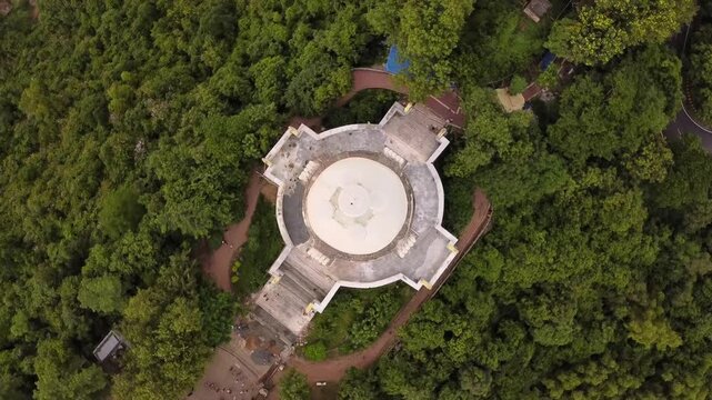 Top Down Aerial Shot of Dhauli Shanti Stupa White Dome Surrounded by Forest on Dhauli Hills. Buddhist Peace Pagoda Architecture in Bhubaneswar Odisha India.