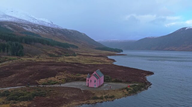 Pink house on loch glass shore in scottish highlands