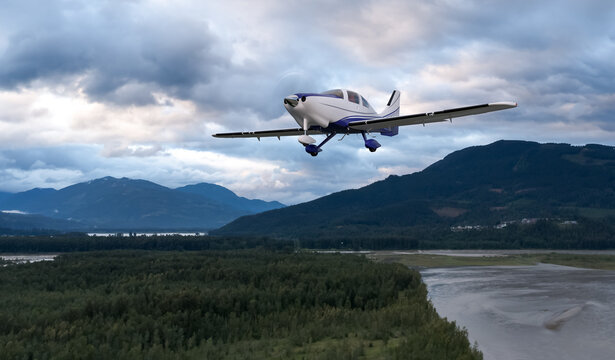Small Single-Engine Airplane Flying Over Forested Mountains With Dramatic Cloudy Sky