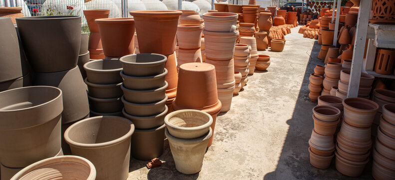 Large outdoor display of terracotta flower pots and clay planters at a garden center in daylight