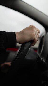 Vertical screen hands controlling steering wheel during driving lesson realistic learning atmosphere inside modern car focused transportation education concept on the road
