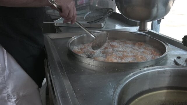 Fresh Turkish lokma dessert production at a street food stand. Golden fried dough sweets prepared in authentic local style.