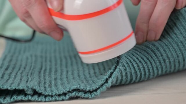 A woman revives the look of her knitted garments with a lint remover.