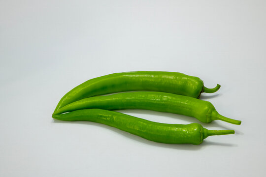Photographic work of indispensable vegetables of the table, dried onions, garlic and green peppers on a white background.