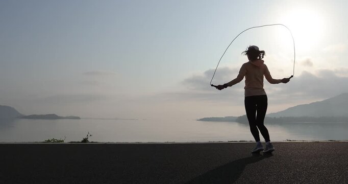 Fitness woman rope skipping at seaside