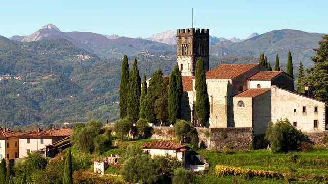Barga Tuscany Aerial 4K. Drone slow crane shot revealing medieval Duomo cathedral on hilltop. Garfagnana valley historic borgo townscape. Majestic Apuan Alps mountain range landscape. part 1