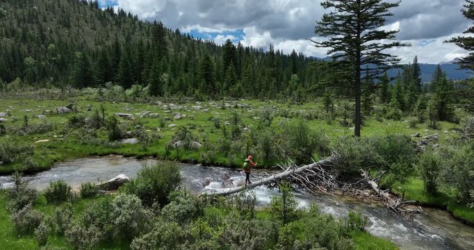 Woman walking on a one plank bridge in high altitude mountains