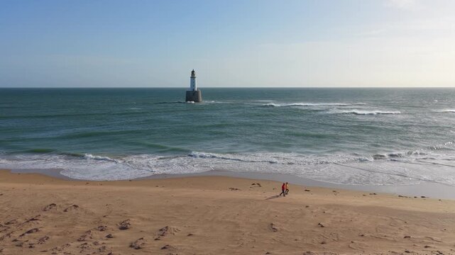 People walking on the beach with rattray head lighthouse
