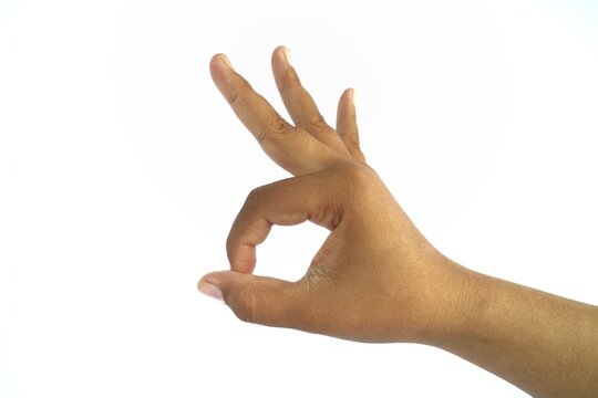 The "OK" hand gesture is formed by bringing the tips of the thumb and index finger together in a circle, while the other fingers remain straight or relaxed.