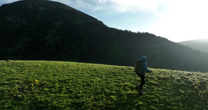 Aerial footage of woman backpacking in the beautiful flowering grassland and forest mountains, slow motion