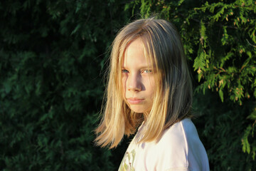 Naklejka premium Portrait of a blonde preteen girl in golden hour sunlight