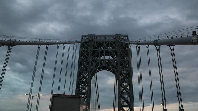 point of view of car driving over george washington bridge between fort lee new jersey and manhattan york heights (sunset night time cloudy suspension bridge)