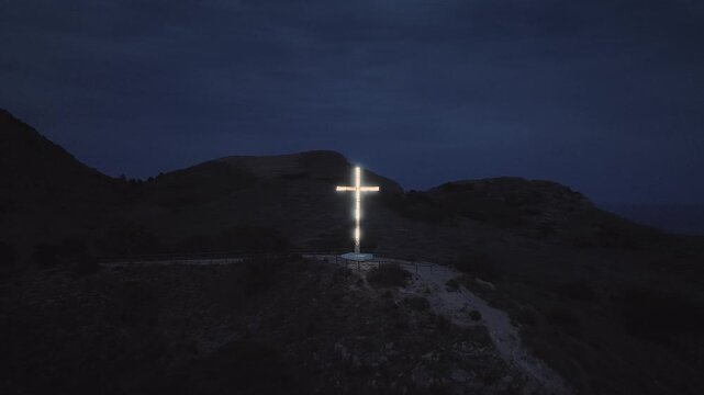 Cross Illuminated on a Dark Mountain Peak at Night Serving as a Powerful Symbol of Faith and Spirituality in a Serene Natural Setting Perfect for Religious Concepts and Cinematic Background