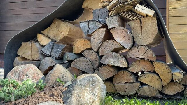 Stacked firewood under rubber sheet close-up showing neatly split logs with rough bark and visible growth rings against wooden shed