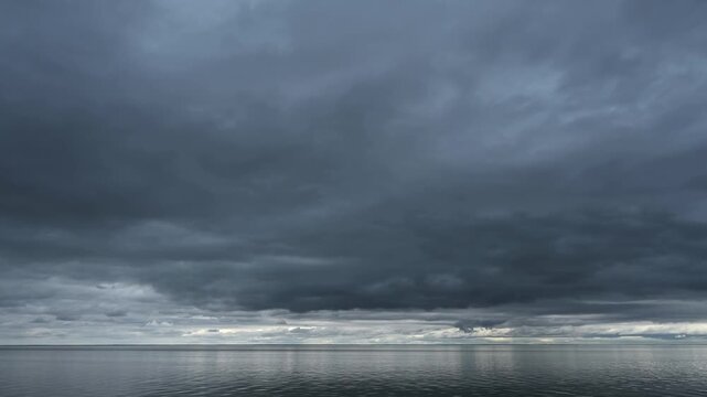 Time lapse of a blue-gray stormy clouds moving across the sky above a large northern lake 
