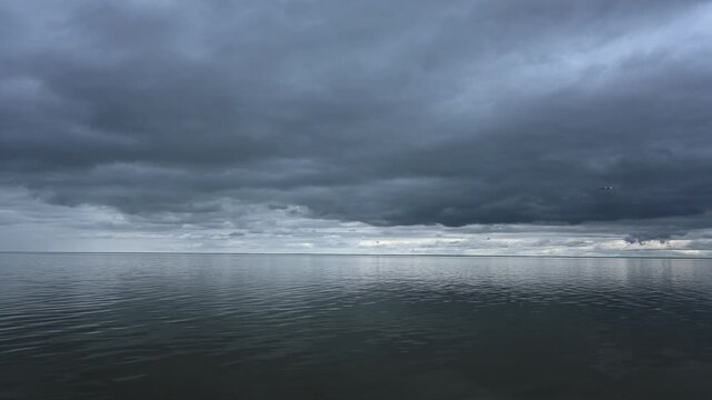 Timelapse of a cloud filled sky above a large lake with small waves
