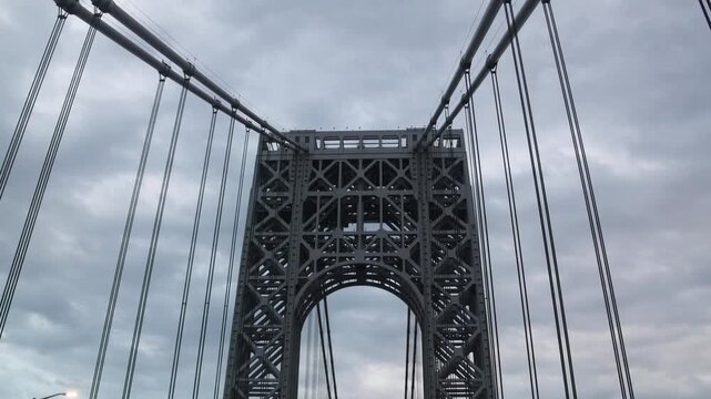 point of view of car driving over george washington bridge between fort lee new jersey and manhattan york heights (sunset night time cloudy suspension bridge)