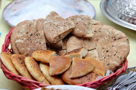Assortment of fresh traditional Moroccan flatbread (Khobz) cut into wedges in a red wicker basket