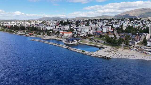 BARILOCHE, ARGENTINA: Aerial drone view of San Carlos de Bariloche along the blue Nahuel Huapi Lake, capturing the waterfront city architecture, pier and scenic beach in Patagonia.