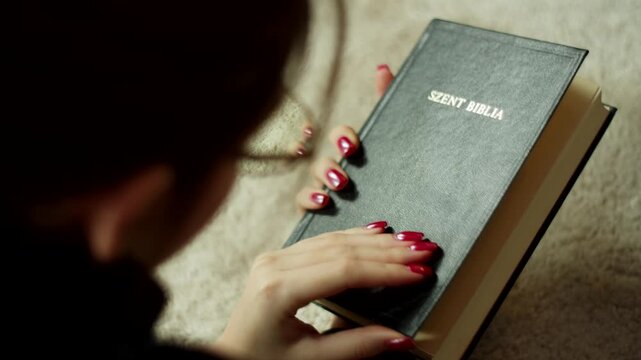 Bible Study at Home with a Woman Lying on the Living Room Floor Reading Through the Contents Page and Touching the Text in a Peaceful Indoor Setting Capturing a Moment of Personal Reflection