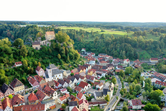 Aerial view of Pottenstein Castle on a rocky hill overlooking the historic town center with its church and traditional red-roofed houses Pottenstein, Bavaria, Germany.