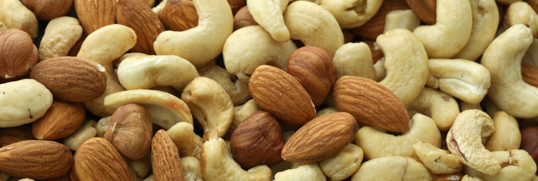 Detailed view on almond and cashew nuts in big pile on table close up
