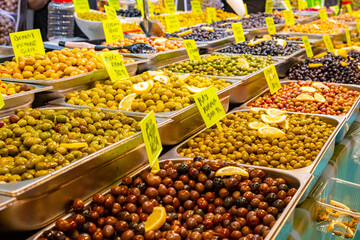 Obraz premium Top view of edible organic black olive pile. Black Olive dried, healthy food on the farmers market stand.A high angle shot of a bowl filled with fresh Papaya seeds. Black olives in conserve in a pot f