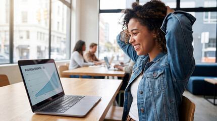Obraz premium Young professional woman smiling while working on laptop in bright modern office with colleagues