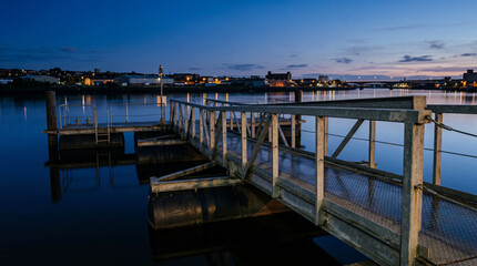 Obraz premium Floating industrial chic steel jetty featuring subtle diamond plate texture resting on calm water surface