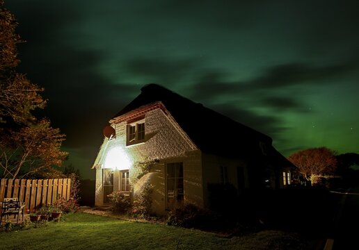 Northern Lights (Aurora borrealis) over a thatched roof house, Junkersmitteldeich, Pellworm Island, Schleswig-Holstein Wadden Sea National Park, North Frisia, Germany