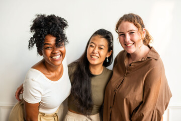 Fototapeta premium Three smiling women of diverse ethnicities posing together indoors