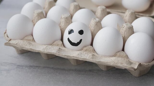 Close-up Hand Painting Smile Face on White Egg