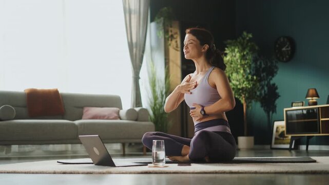 Yoga instructor leading an online fitness class from home while using a tablet during a virtual wellness and workout session.