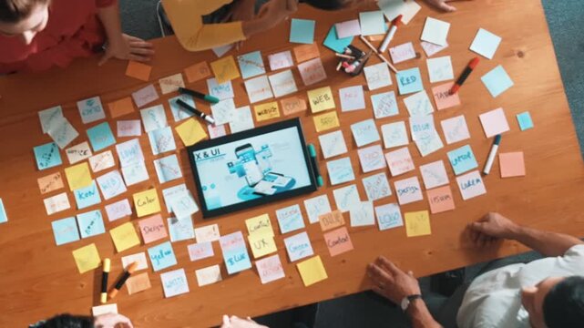 Top view of smart business team shaking hand or making agreement at meeting table with tablet display wireframe prototype for mobile phone or computer. Aerial view of team working together. Symposium.