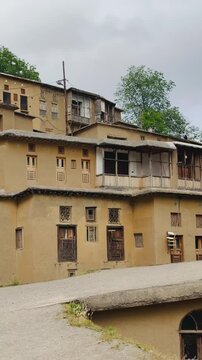 Traditional stepped clay houses with carved wooden windows in a historic mountain village, panning shot from left to right, vertical 9:16 video.