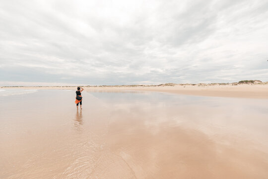 Woman on the beach taking photos with camera of distant birds