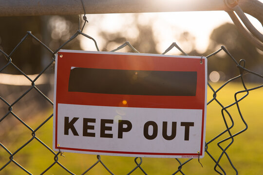 close up of an old keep out sign on a damaged fence