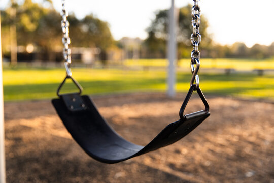 black rubber swing seat at a local park with blurry background
