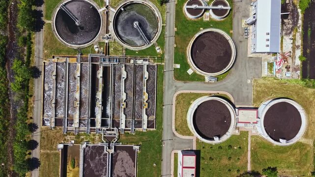 Aerial wastewater treatment plant showing circular clarifiers and aeration basins utility operator conducts drone survey for maintenance and sustainability