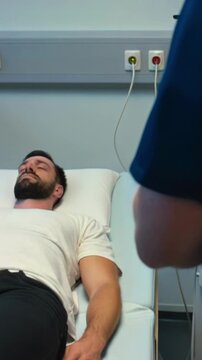 Clinician reviews electrocardiogram while patient rests peacefully. Healthcare professional carefully examines ECG waveform displayed on monitor as patient remains calm and at ease