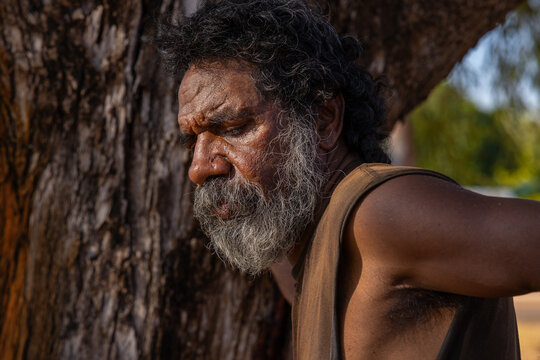 head and shoulders of middle-aged Aboriginal man in profile against a tree