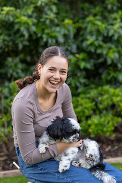 teen girl playing with pet dog in front of garden greenery