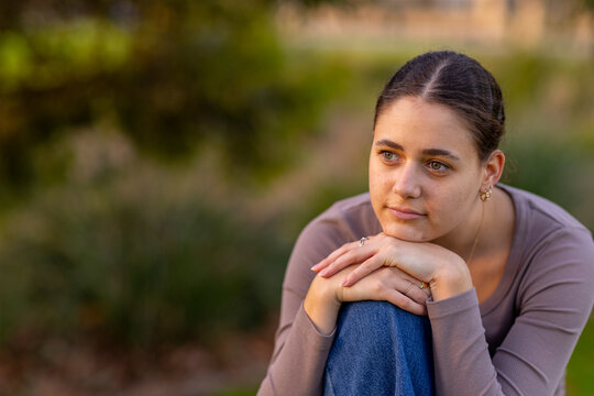 head and shoulders of teen girl looking off into distance with copy space and blurry background