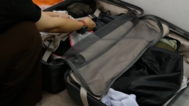 Happy Asian traveler packing luggage in bedroom before journey, vacation planning lifestyle theme