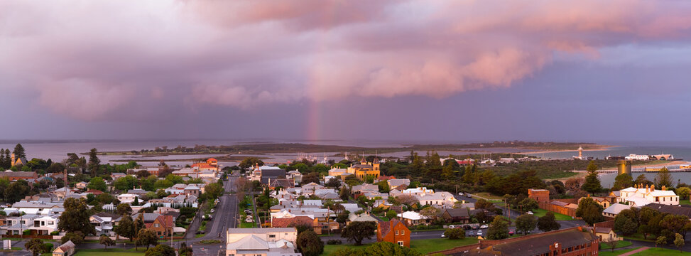 Aerial view of a rainbow in a dramatic coloured sky over historic buildings in a coastal town