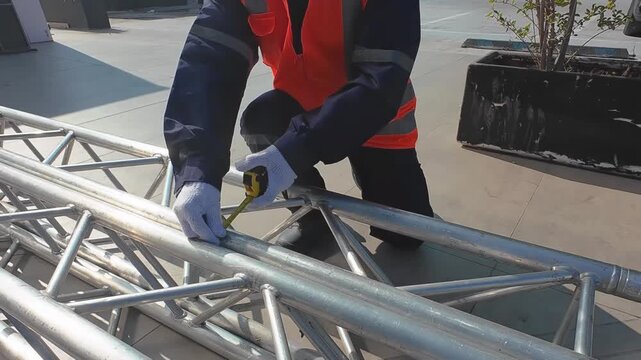 Technician Measuring Metal Structure With Tape Measure in Industrial Environment