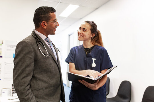 Doctors reviewing notes in clinic hallway
