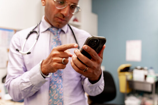 Medical professional checking relevant message on his smartphone in clinic office