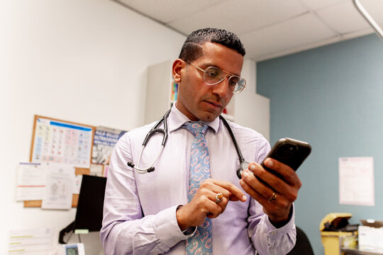 Medical doctor reviewing smartphone in clinical office